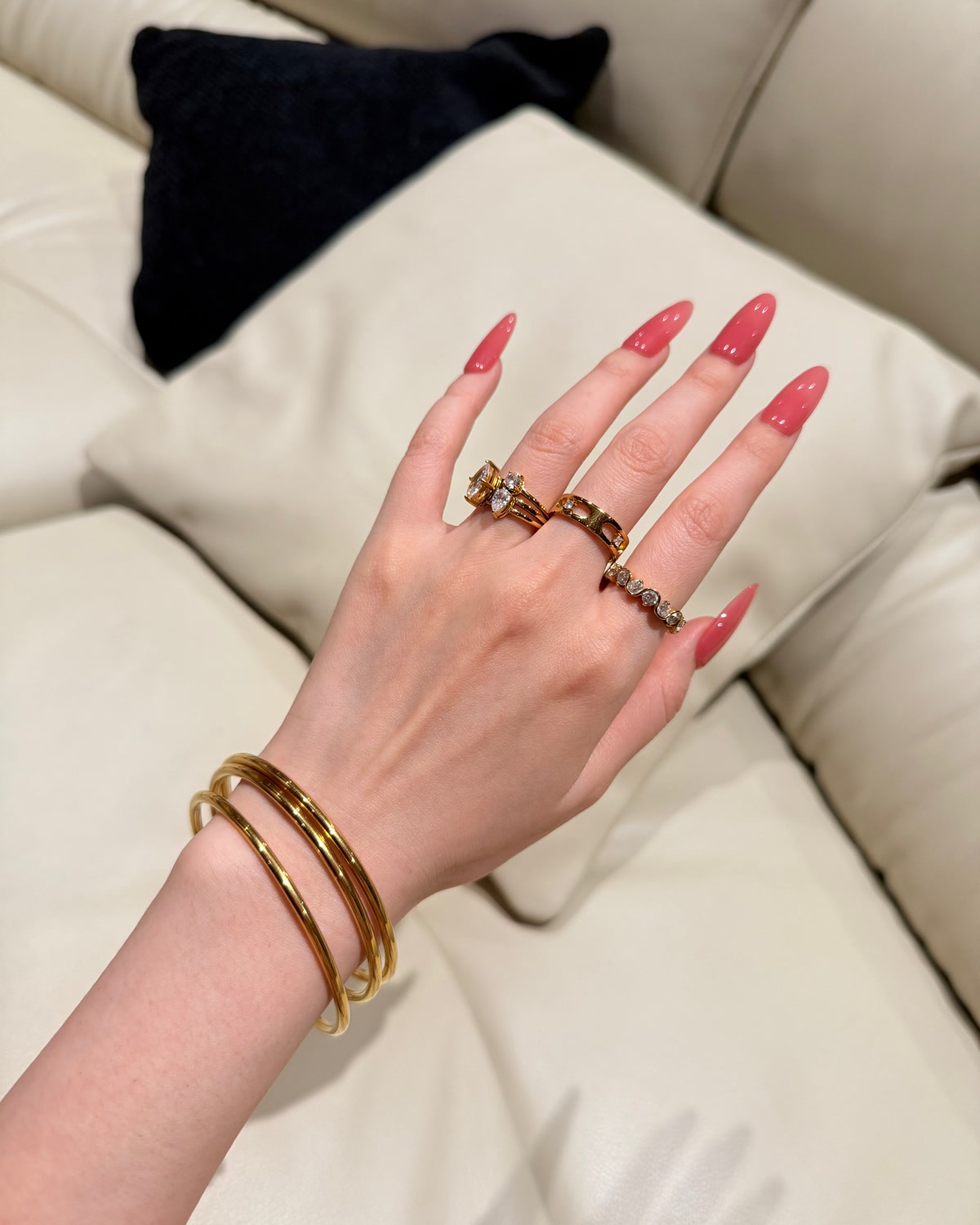 A real wearer combining multiple gold rings with slim gold bangles